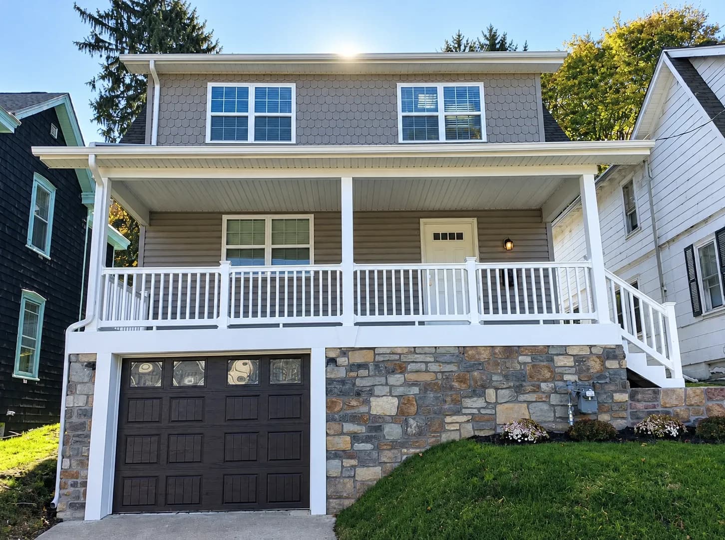 The same Conshohocken house after Giuliani Builders renovated the exterior: new siding, a white-railed front porch, stone veneer, and a new garage door