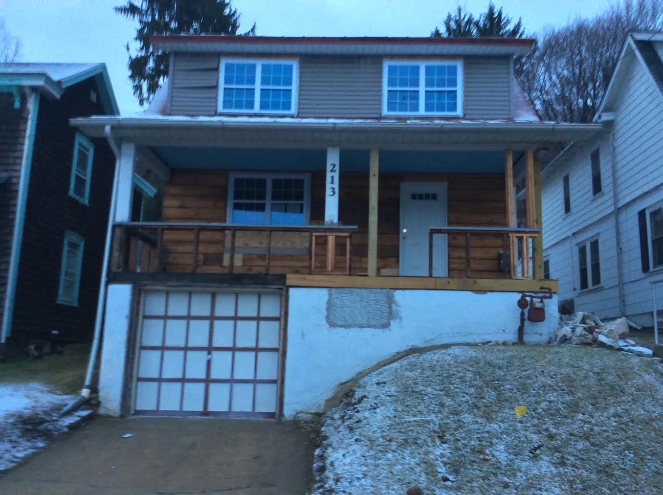 House in Conshohocken, PA before the renovation, with a bare wood porch, worn siding, and a plain stucco garage wall