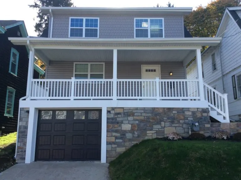 House with a covered front porch above a stone-faced garage