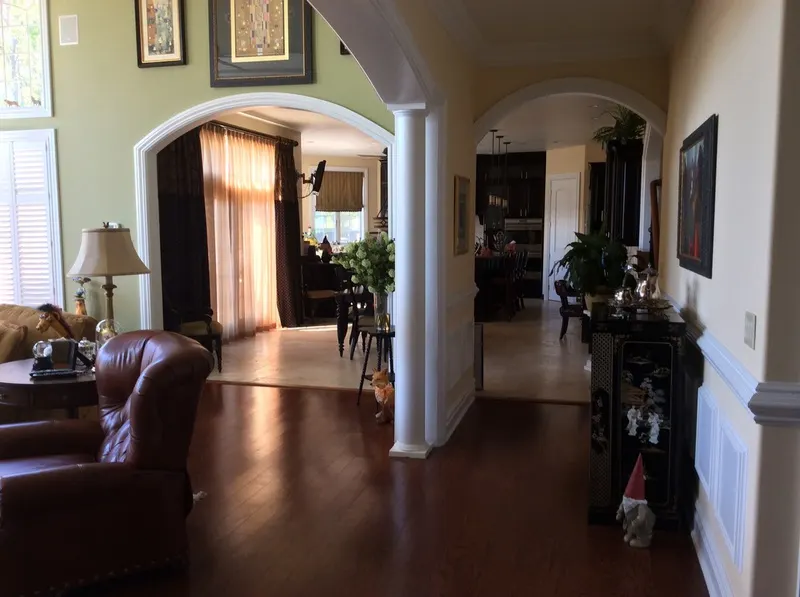 Living room with arched openings, white columns, and dark wood floors